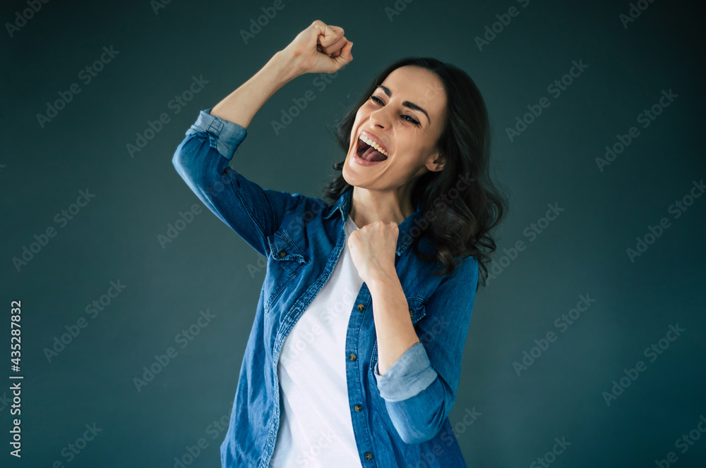 Beautiful excited happy winner woman is shouting and celebrating on gray background Beautiful excited happy winner woman is shouting and celebrating on gray background