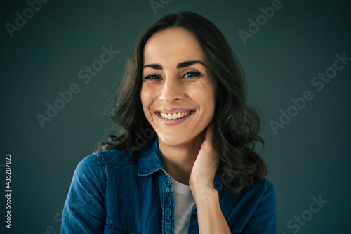 Close up portrait of a smiling attractive young brunette  woman on gray wall background