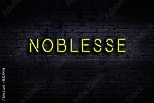 Night view of neon sign on brick wall with inscription noblesse photo