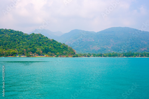 Beautiful tropical landscape. Blue sea and mountains overgrown with vegetation on the coast