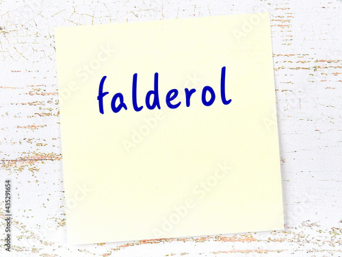 Yellow sticky note on wooden wall with handwritten word falderol photo