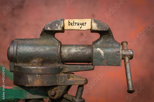 Vice grip tool squeezing a plank with the word betrayer Fototapet