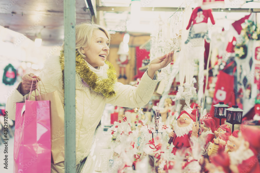 Smiling woman is buying Christmas ornamentals in the market outdoor.