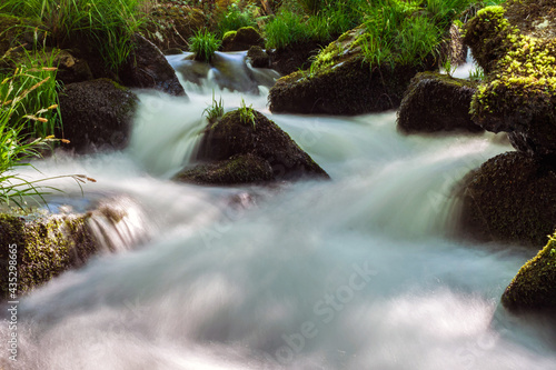 Small and beautiful mountain river in Galicia. The water of a stream falls gently on the rocks with moss forming small and beautiful waterfalls