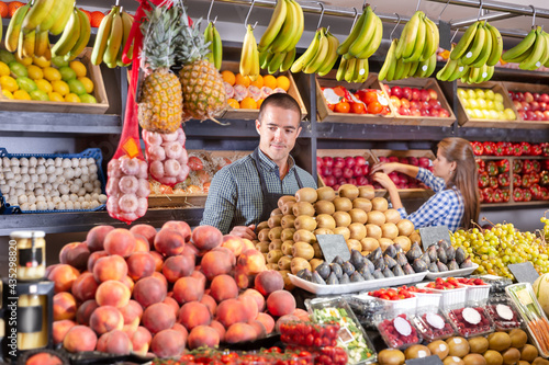 Portrait of male and female young shop assistants working responsibly in the fruit and vegetable shop photo
