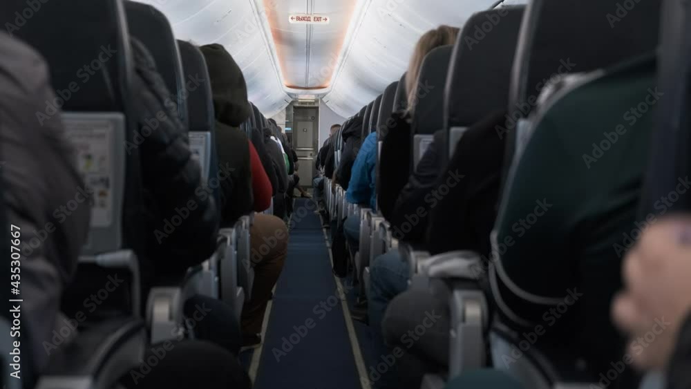 Jet airplane interior view with unrecognizable passengers in comfortable seats of aircraft. Sign Exit. Jet airplane interior view with unrecognizable passengers in comfortable seats of aircraft. Sign Exit.