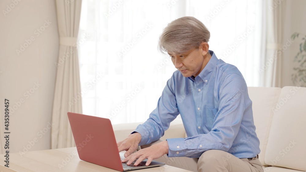 リビングでパソコンを楽しむミドル男性