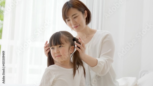 女の子の髪を結ぶ女性
