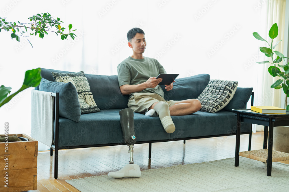 Fototapeta premium タブレットで映画を見る義足の男性