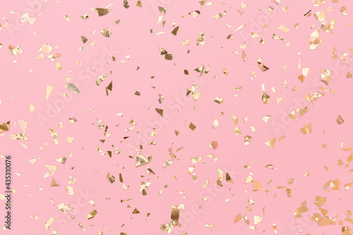 Gold confetti sparkles on pastel pink background, golden foil, chic holidays.