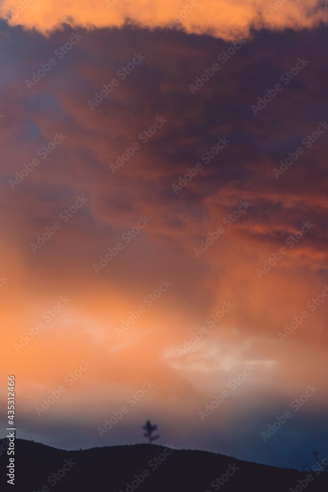 beautiful intense sunset sky with pink and golden tones over the mountains and trees