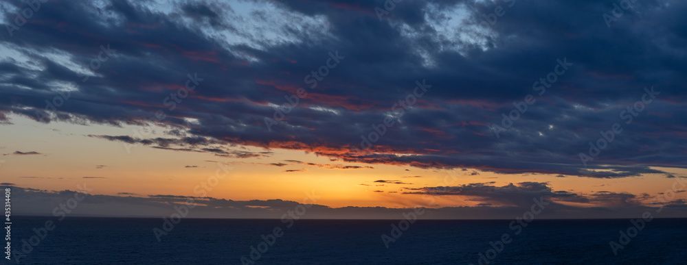 An evening cloudscape panorama with vivid colors in the sky and dark clouds.