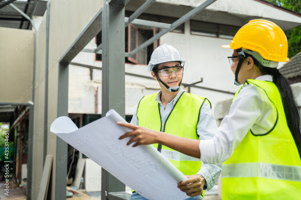 Asian male engineer explaining job on blueprint to female worker. Asian male engineer explaining job on blueprint to female worker.