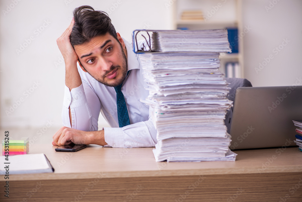 Young businessman employee unhappy with excessive work in the office Young businessman employee unhappy with excessive work in the office