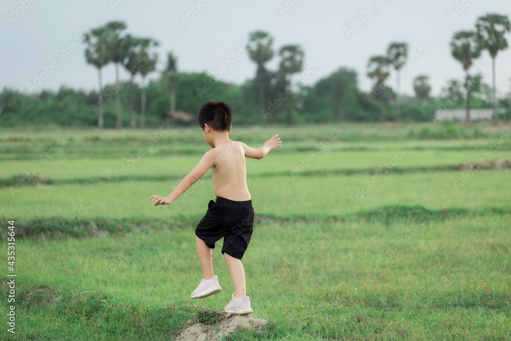 happy little Asian boy run on the field happy little Asian boy run on the field