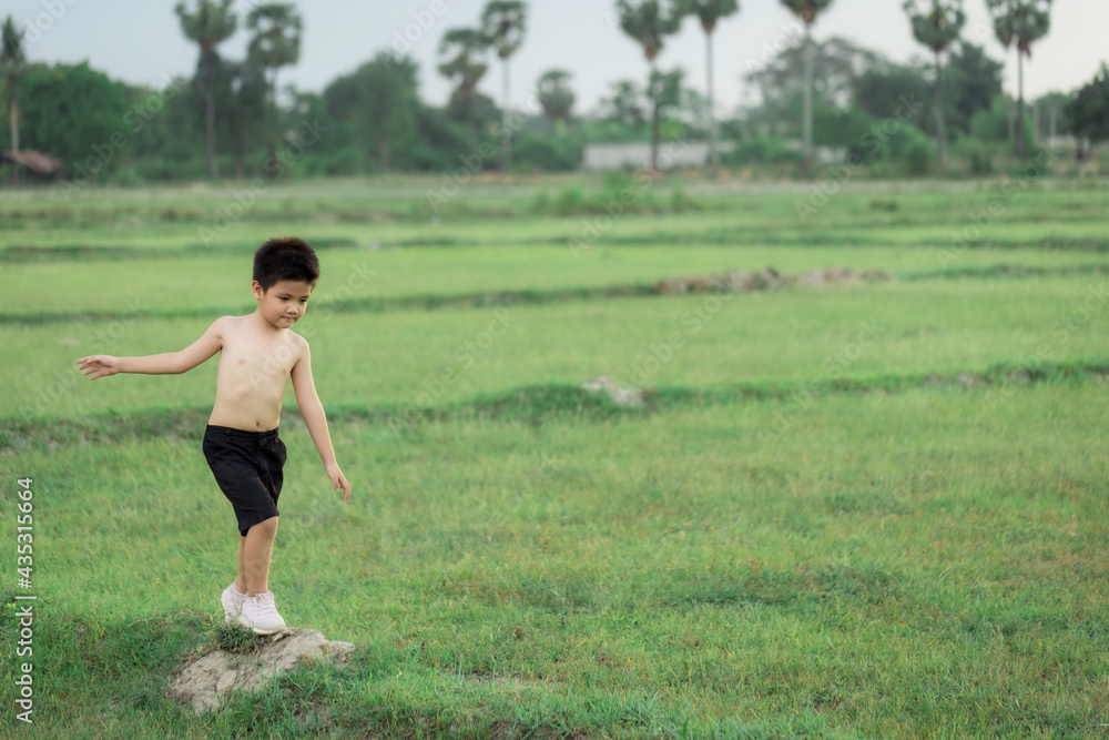 happy little Asian boy run on the field happy little Asian boy run on the field