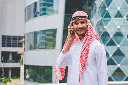 Islamic man using smartphones app organize schedule agenda  focus on hands holding smartphone muslim modern uae city. Arab men wear hijab and muslim formal dress sending text sms online lifestyle photo