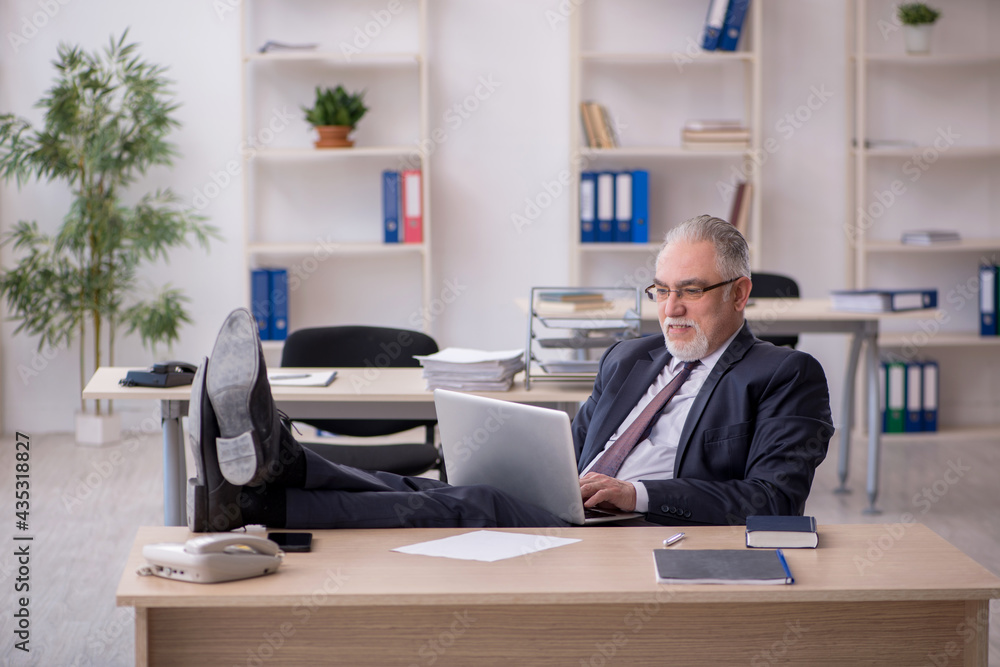 Old male employee sitting at workplace Old male employee sitting at workplace