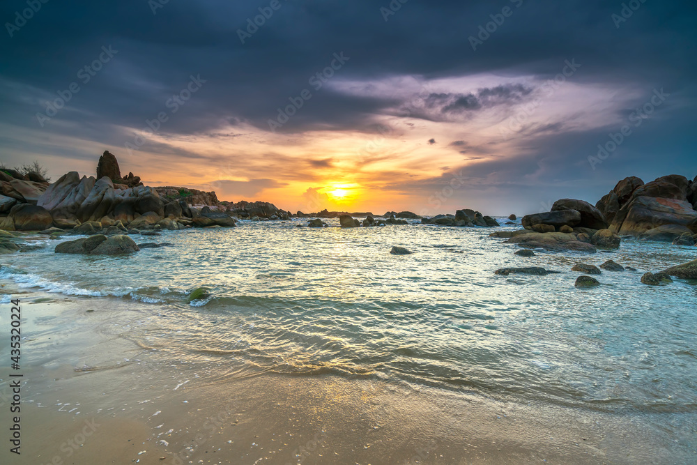 Fototapeta premium Beautiful sunrise on the beach below the waves lapping at the shore of the soft great to welcome the peaceful new day