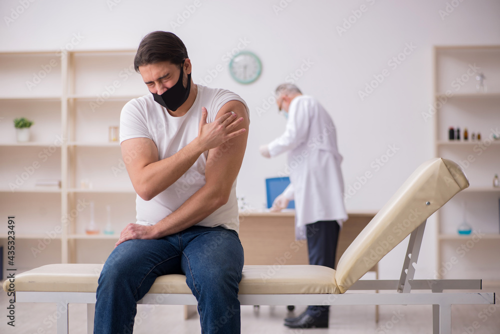 Obraz premium Young male patient visiting old doctor in vaccination concept