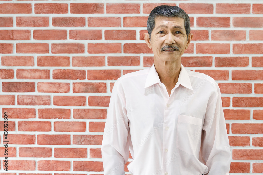 Portrait Closeup shot of handsome old male senior pensioner grandfather with gray hair and mustache standing smiling look at camera in front of red brick wall background with copy space for text Portrait Closeup shot of handsome old male senior pensioner grandfather with gray hair and mustache standing smiling look at camera in front of red brick wall background with copy space for text