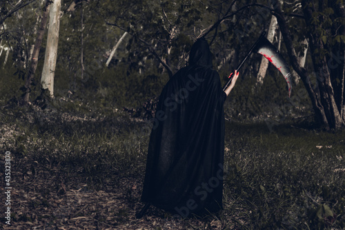 Back woman horror ghost holding reaper in forest, halloween concept