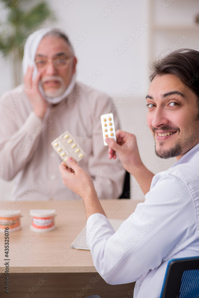 Old male patient visiting young male doctor dentist Old male patient visiting young male doctor dentist