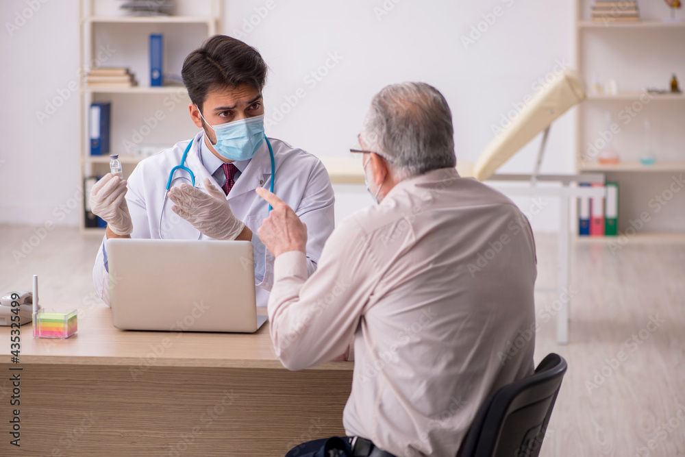 Fototapeta premium Old male patient visiting young male doctor in vaccination conce