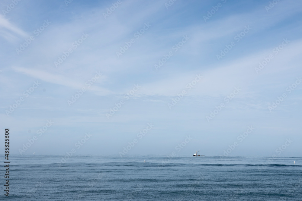 A Fishing Boat Sails Over the Vast Blue Ocean