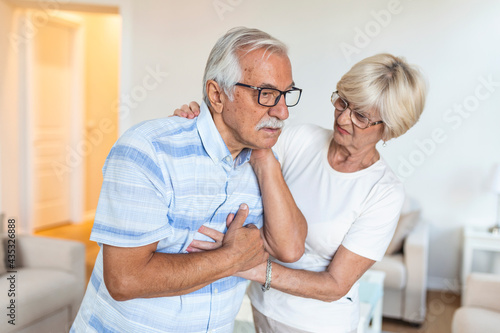 Senior man with neck pain and concerned elderly woman at home