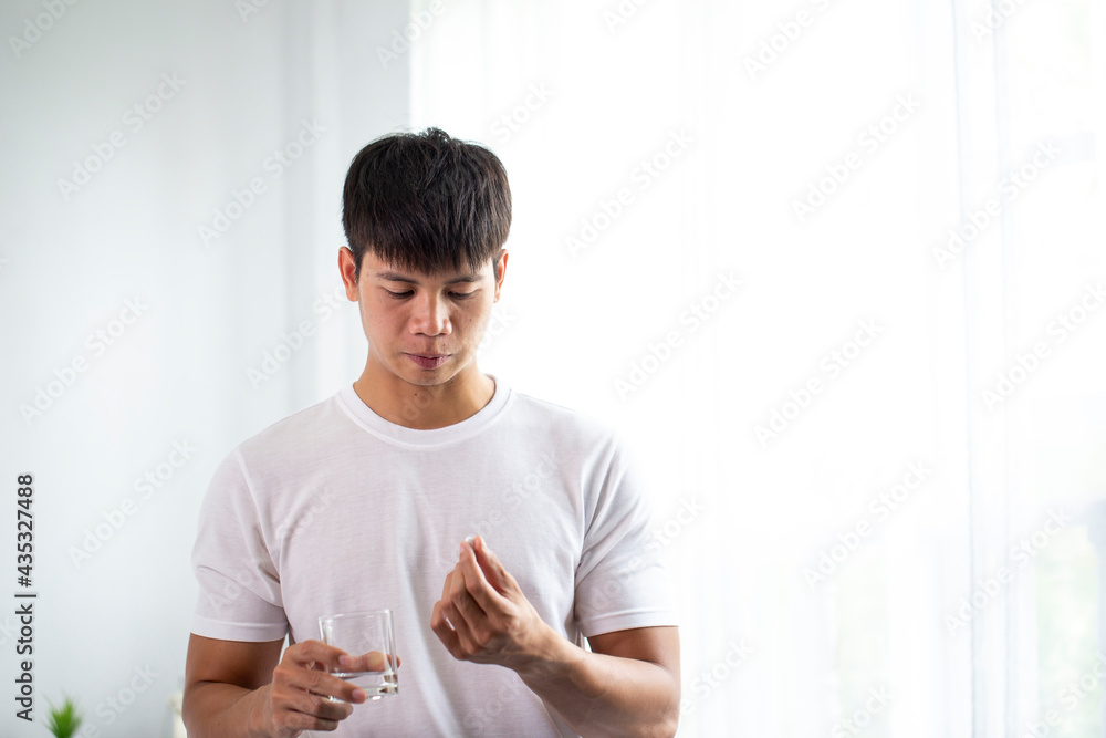 Sick asia man having fever, drinking hot healing tea and touching forehead in bed. a sick man in the background, flu. Epidemic, sick leave, temperature, stress. Sick asia man having fever, drinking hot healing tea and touching forehead in bed. a sick man in the background, flu. Epidemic, sick leave, temperature, stress.