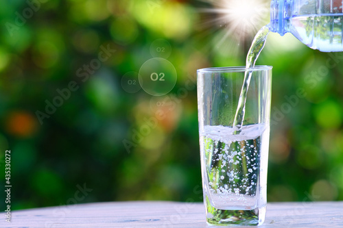  Close up pouring purified fresh drink water from the bottle on wooden table and mineral water health care concept, space for text
