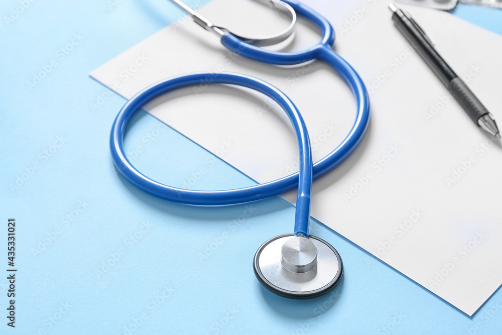 Modern stethoscope and sheet of paper on color background, closeup Modern stethoscope and sheet of paper on color background, closeup
