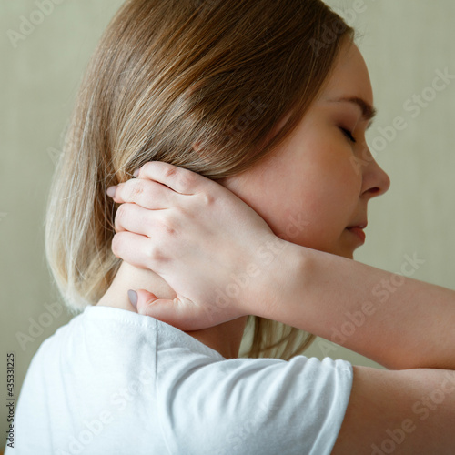 Woman holds neck with pain cervical muscle spasm by hand. Neck pain, cervical vertebrae, Disease of musculoskeletal system in young woman. Square