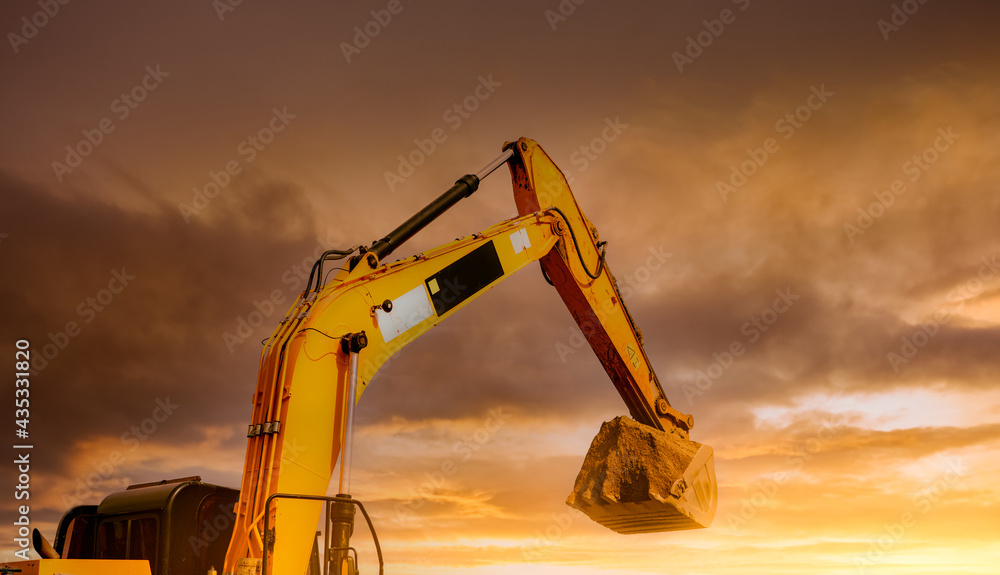 Backhoe working by digging soil at construction site. Closeup hydraulic ...