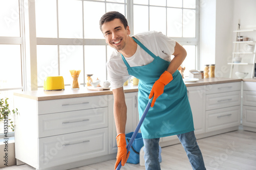 Young man mopping floor in ...