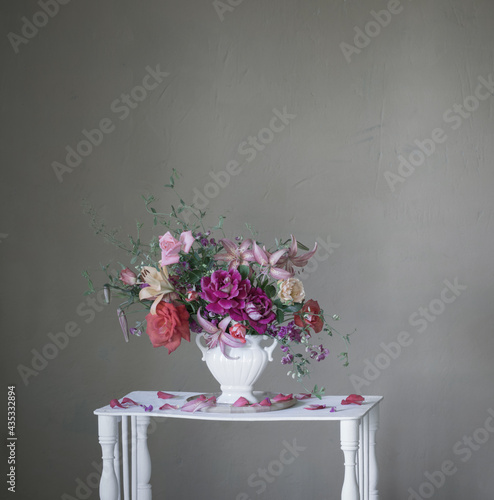 bouquet of summer flowers in vase on vintage white wooden shelf photo