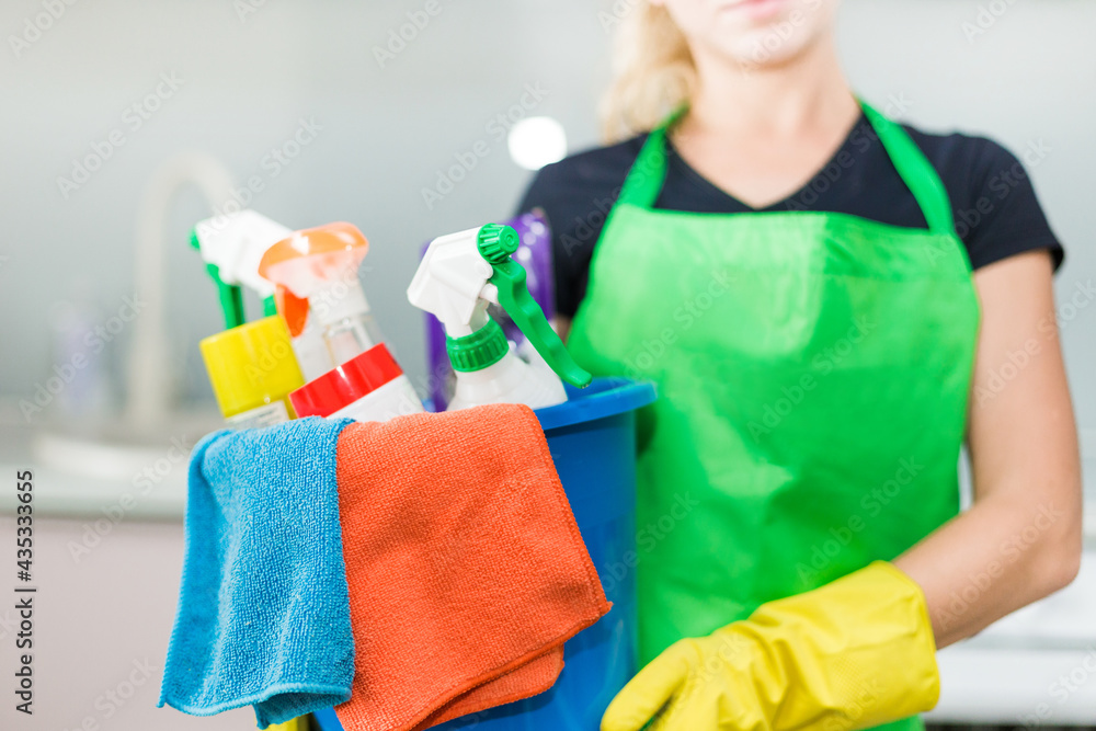 Young woman holding bucket with group of cleaning supplies for natural and environmentally friendly cleaning. Household equipment, tidying up, cleaning service concept, copy space Young woman holding bucket with group of cleaning supplies for natural and environmentally friendly cleaning. Household equipment, tidying up, cleaning service concept, copy space