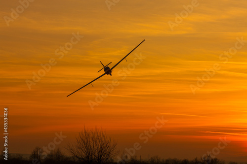 Small backlit airplane above ground in the sunset