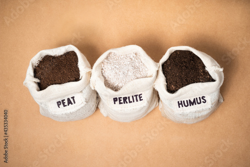 Peat moss, perlite and worm humus as potting soil materials in rustic fabric bags on a mdf surface with copy space. photo