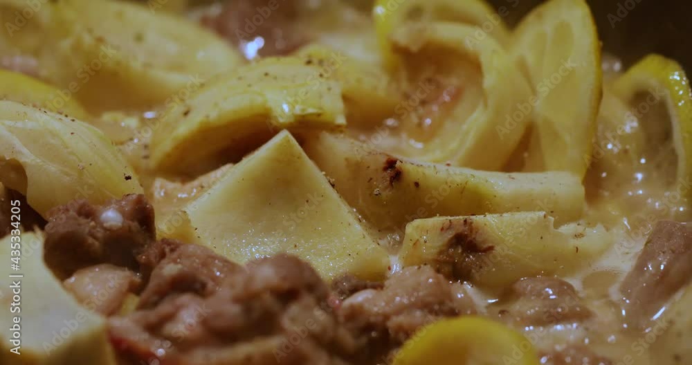 Young calf meat with lemon and potatoes is boiled in large cauldron, boiling and bubbling Young calf meat with lemon and potatoes is boiled in large cauldron, boiling and bubbling