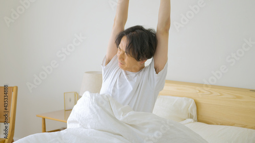 朝起きてベッドの上でストレッチをする男性