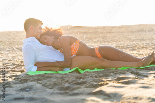 multiracial happy couple on the beach, lying top each other photo