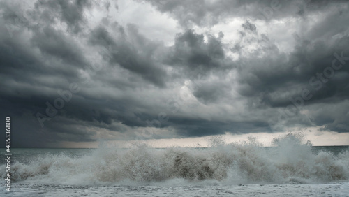 View of a stormy sea and dramatic cloudy sky, big waves are crashing on the shore