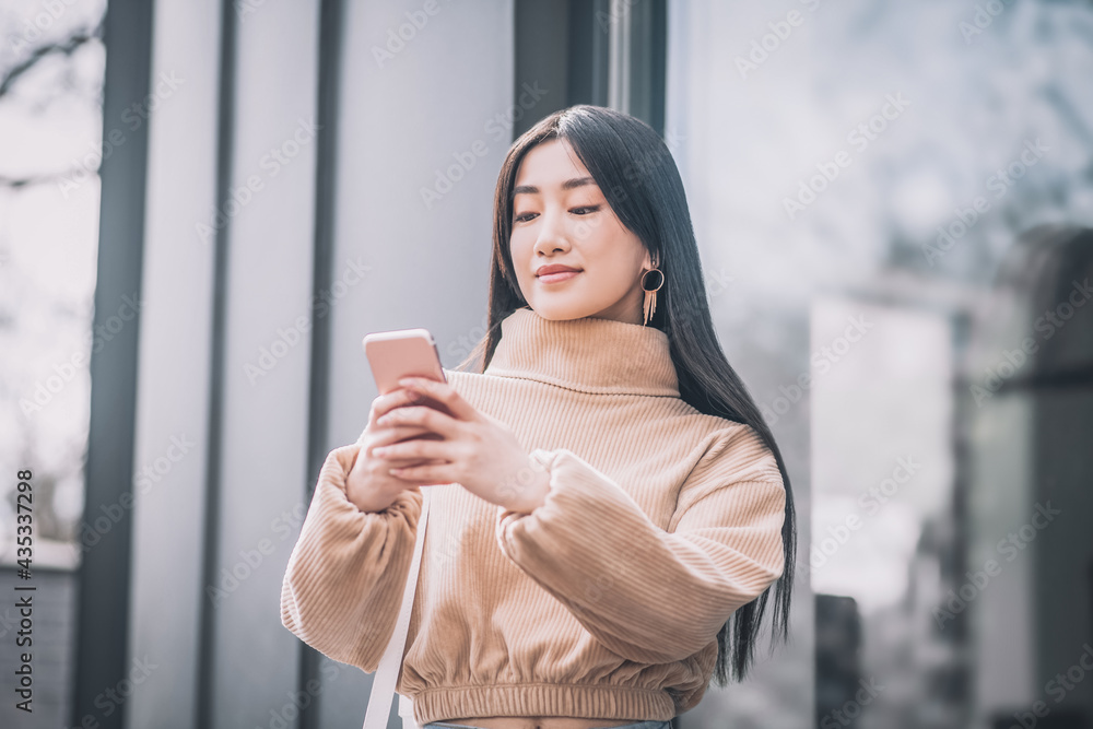 Pretty young asian woman holding a smartphone in her hands