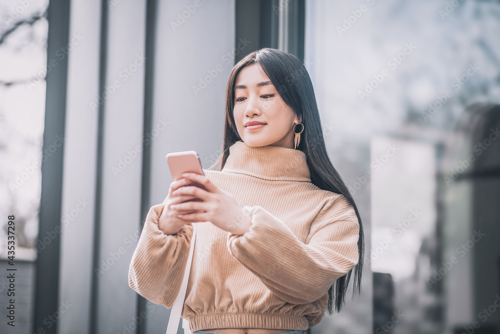 Pretty young asian woman holding a smartphone in her hands Pretty young asian woman holding a smartphone in her hands