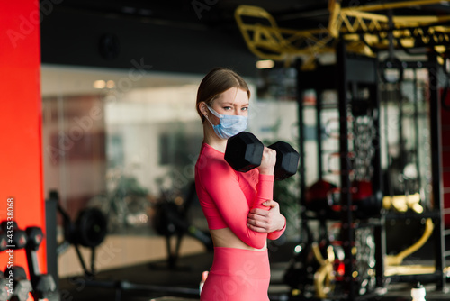 Woman wearing face mask exercise workout in gym during corona virus pandermic.