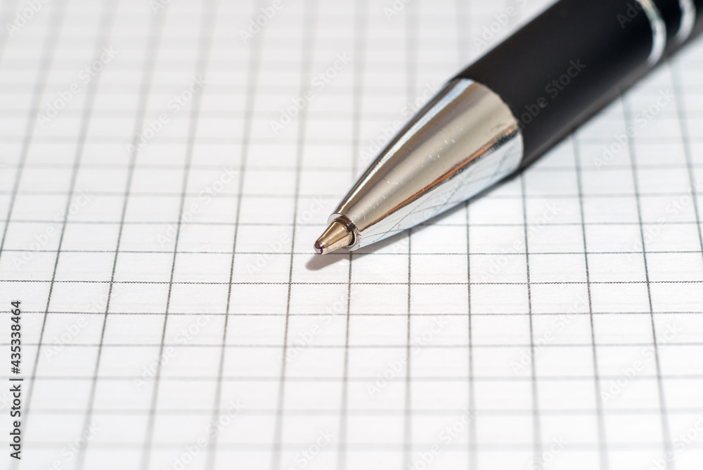 Ballpoint pen on the background of a sheet of checkered paper Ballpoint pen on the background of a sheet of checkered paper