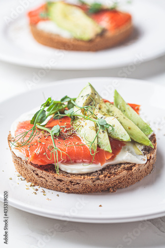 Breakfast toast with cream cheese, salmon and avocado, white background.