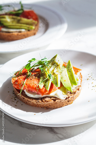 Breakfast toast with cream cheese, salmon and avocado, white background.